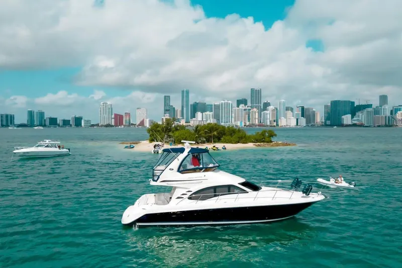 Slide: The Image of 2005 Sea Ray 420 Sedan Bridge yacht cruising near a city skyline and small island. - 7