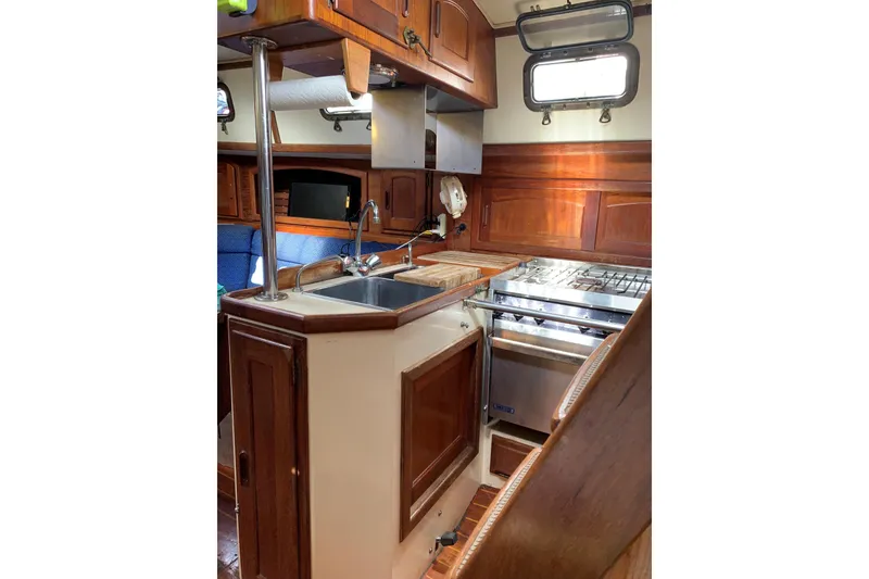 Slide: The Image of Interior of 1993 Pacific Seacraft 37 sailboat galley with wood cabinetry and stainless steel appliances. - 12