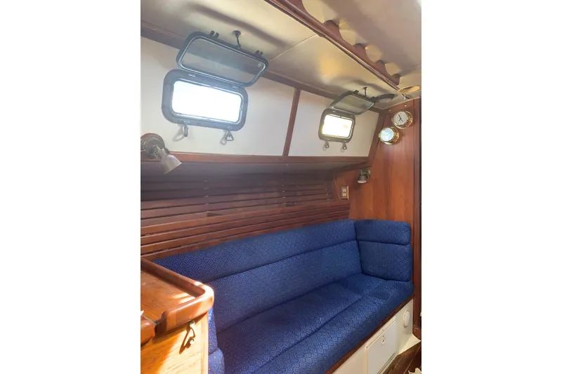 Slide: The Image of Interior of 1993 Pacific Seacraft 37 sailboat with blue cushioned seating and wooden paneling. - 8