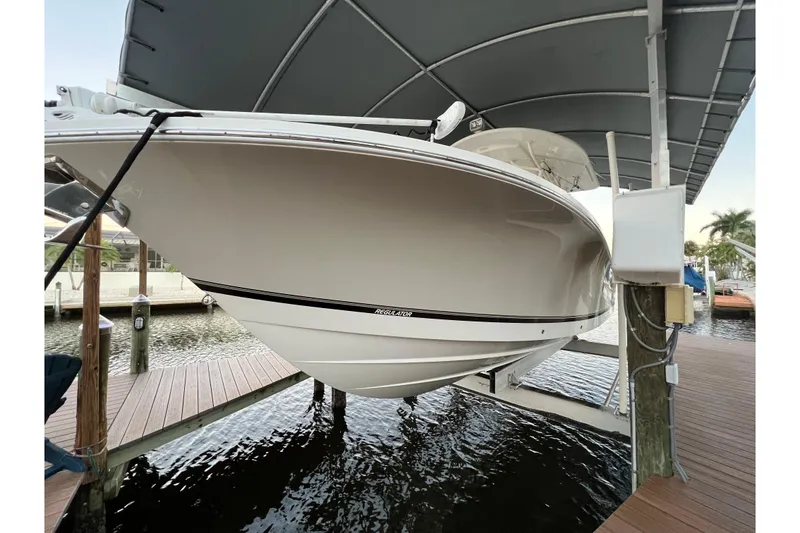 Slide: The Image of 2018 Regulator 28 boat on lift under canopy at marina dock. - 28