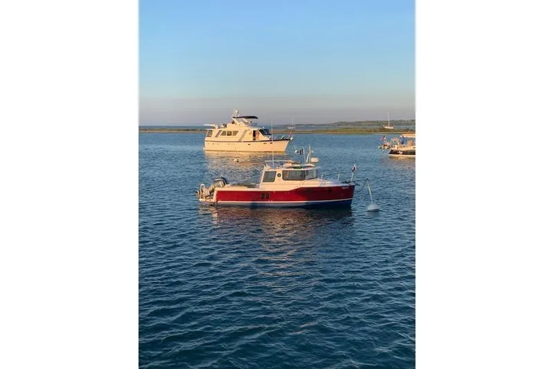 Slide: The Image of 2022 Ranger Tugs R-25 boat anchored on calm water at sunset. - 10