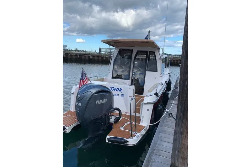 Slide: The Image of 2022 Ranger Tugs R-25 boat docked, featuring Yamaha outboard motor and American flag. - 11