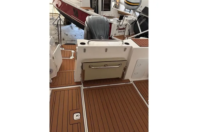 Slide: The Image of 2022 Ranger Tugs R-25 boat deck with teak flooring and outboard motor. - 15