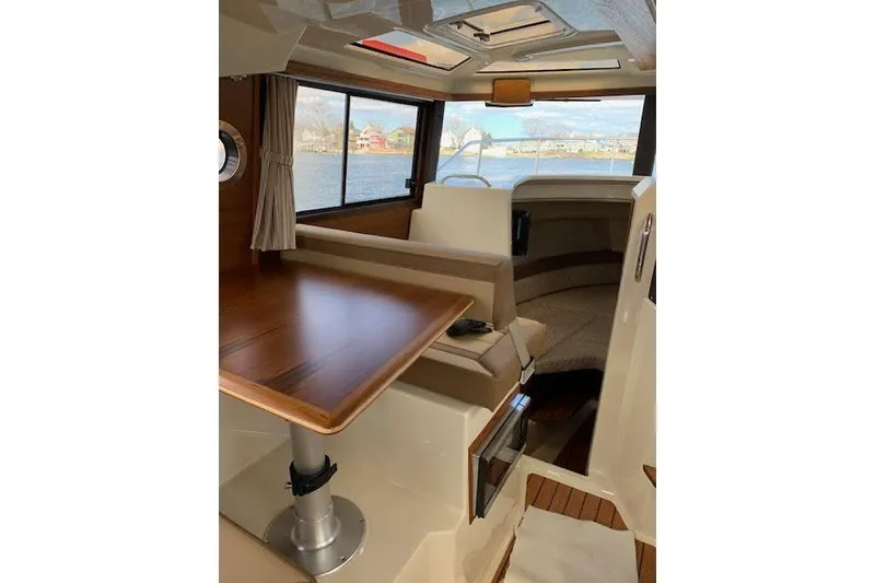 Slide: The Image of 2022 Ranger Tugs R-25 interior with wood table, seating, and scenic window view. - 21