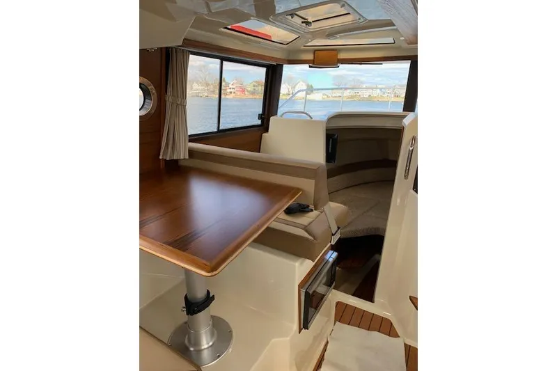 Slide: The Image of 2022 Ranger Tugs R-25 interior with wood table, seating, and windows overlooking water. - 24