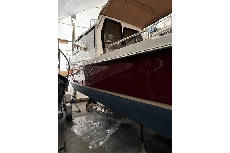 Slide: The Image of 2022 Ranger Tugs R-25 boat in storage, featuring a sleek red and blue hull. - 30