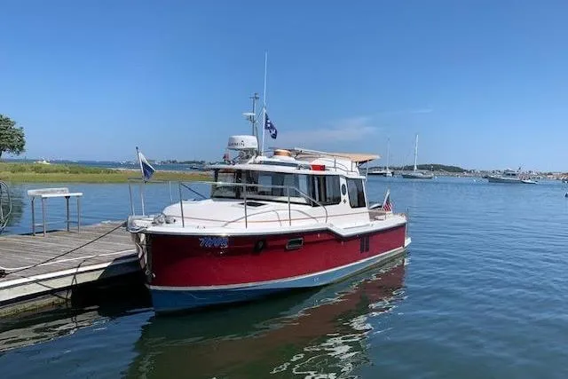 Slide: The Image of 2022 Ranger Tugs R-25 boat docked on calm water under clear blue sky. - 4