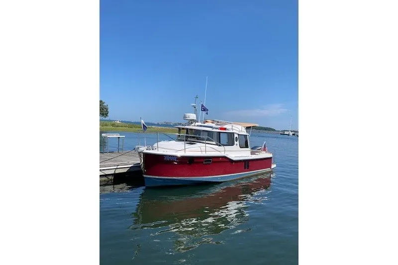Slide: The Image of 2022 Ranger Tugs R-25 boat docked on calm water under clear blue sky. - 5