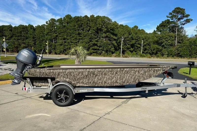 The Image of 2026 Thor 1754 Fish Hammer boat on trailer, camo design, Yamaha motor, outdoor setting. - 1