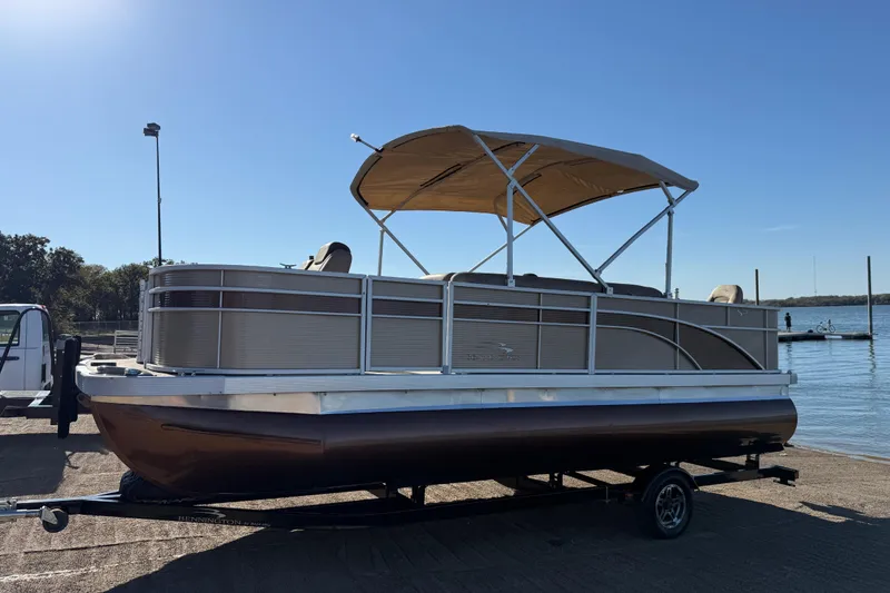 Slide: The Image of 2020 Bennington 21SF pontoon boat on trailer by a lake under clear blue sky. - 103