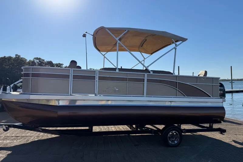 Slide: The Image of 2020 Bennington 21SF pontoon boat on trailer by a lake under clear blue sky. - 104