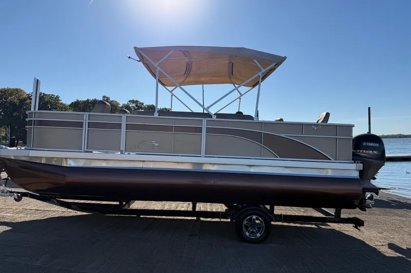 Slide: The Image of 2020 Bennington 21SF pontoon boat with canopy on trailer by the water. - 105
