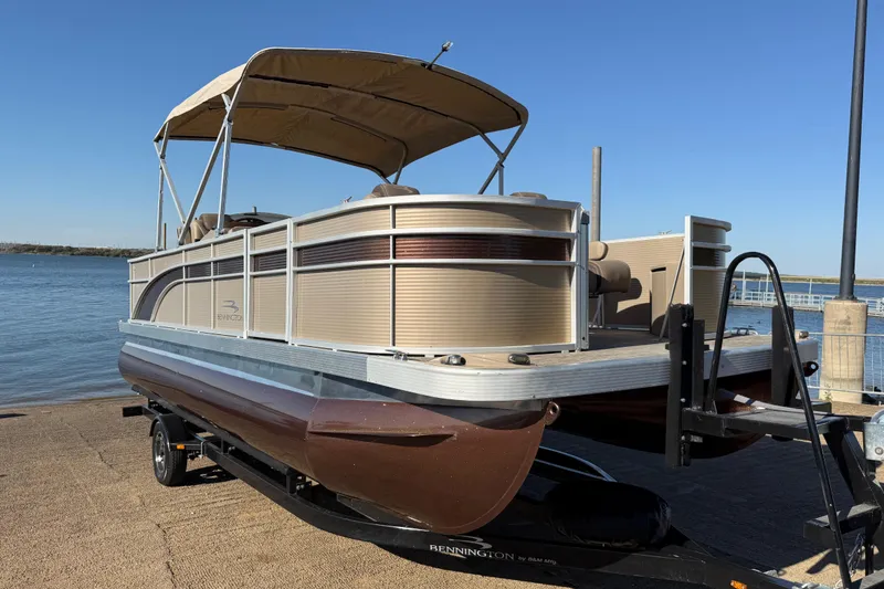 Slide: The Image of 2020 Bennington 21SF pontoon boat with canopy on trailer by the water. - 110