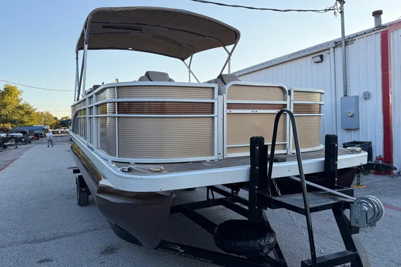 Slide: The Image of 2020 Bennington 21SF pontoon boat on trailer, parked outdoors near a building. - 23