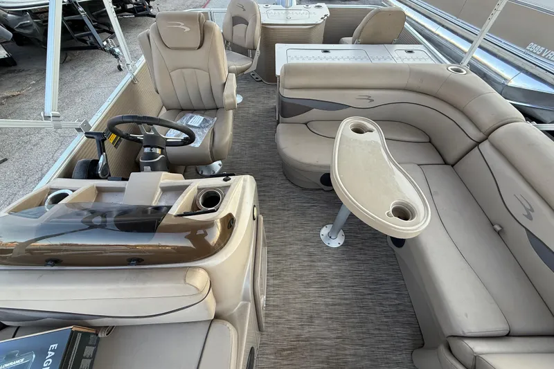 Slide: The Image of 2020 Bennington 21SF boat interior with beige seating and table, docked outdoors. - 40