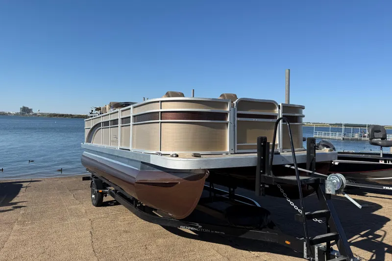 Slide: The Image of 2020 Bennington 21SF pontoon boat on trailer by the water, under clear blue sky. - 71