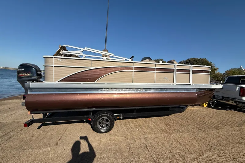 Slide: The Image of 2020 Bennington 21SF pontoon boat on trailer by the water, under clear blue sky. - 75