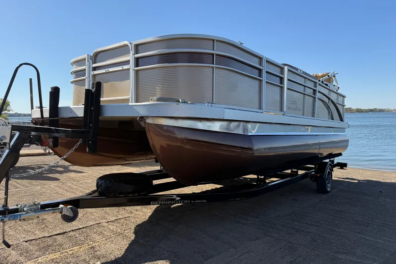 Slide: The Image of 2020 Bennington 21SF pontoon boat on trailer by a lake. - 84