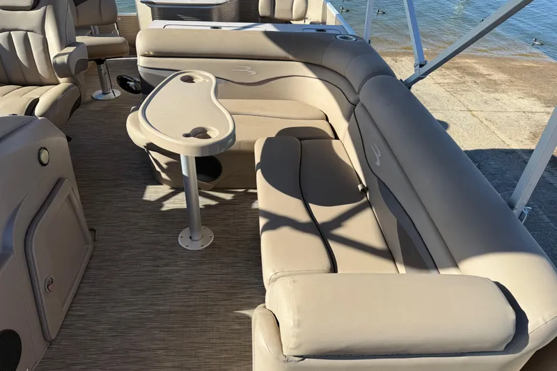 Slide: The Image of 2020 Bennington 21SF pontoon boat interior with beige seating and steering wheel, docked by the water. - 93