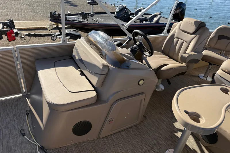 Slide: The Image of 2020 Bennington 21SF boat interior with beige seating and table, docked by the water. - 94