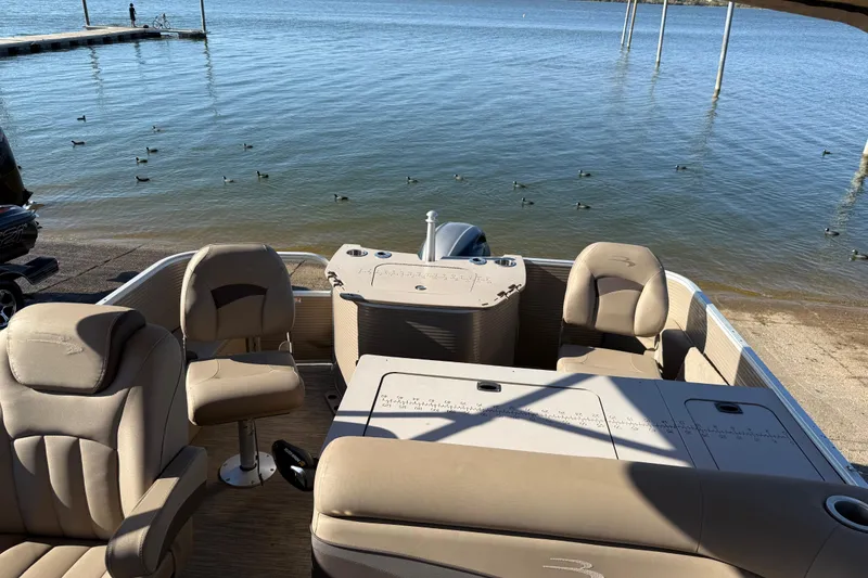 Slide: The Image of 2020 Bennington 21SF boat interior with steering console and seating, docked by the water. - 95