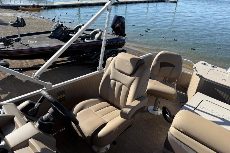 Slide: The Image of 2020 Bennington 21SF pontoon boat interior with beige seating by a lake. - 96