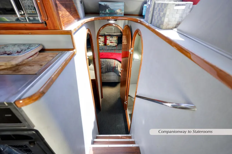 Slide: The Image of Companionway to staterooms on 1993 Mediterranean 38 Convertible yacht, featuring wood accents and cozy decor. - 11