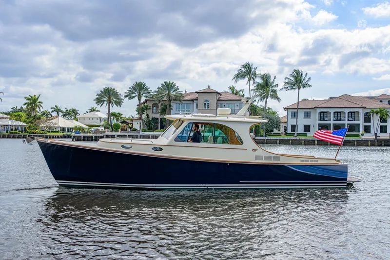 Slide: The Image of 2017 Hinckley Picnic Boat 37 MKIII cruising on a scenic waterfront with palm trees. - 1