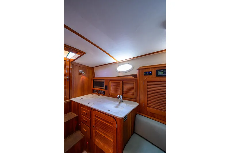 Slide: The Image of 2017 Hinckley Picnic Boat 37 MKIII interior with wooden cabinetry and compact kitchen area. - 28