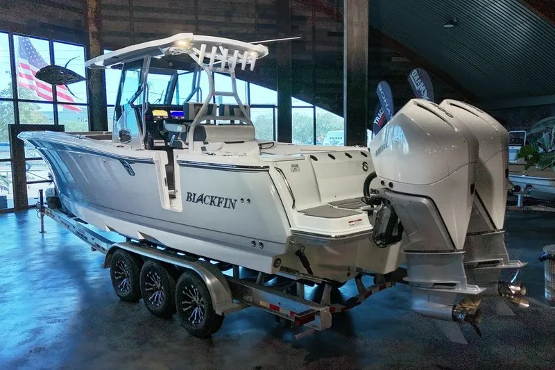 Slide: The Image of 2023 Blackfin 302 CC boat on trailer in showroom with dual engines. - 2