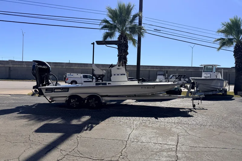 Slide: The Image of 2024 SCB R24 boat with Suzuki engine on trailer, parked near palm trees. - 54