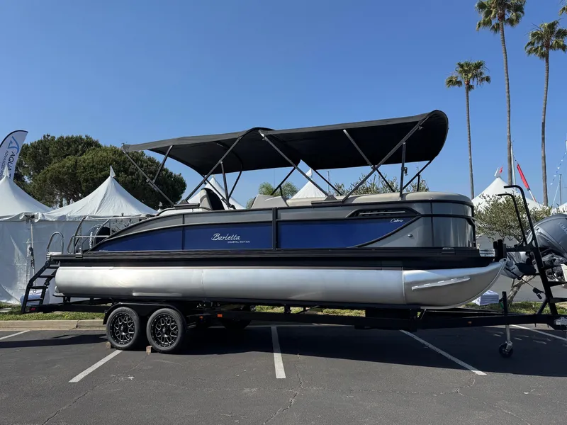 Slide: The Image of 2026 Barletta Cabrio 24U pontoon boat on trailer, displayed outdoors under clear sky. - 2
