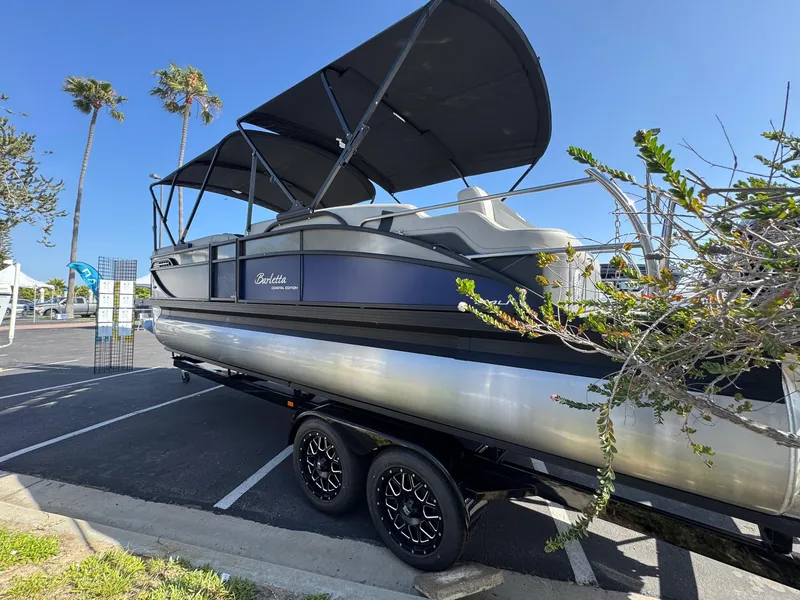 Slide: The Image of 2026 Barletta Cabrio 24U pontoon boat on trailer, parked under clear blue sky. - 7