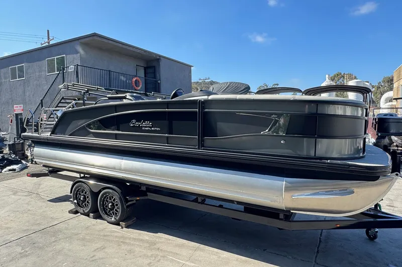 Slide: The Image of 2026 Barletta Lusso 23UC pontoon boat on trailer, parked outdoors. - 123