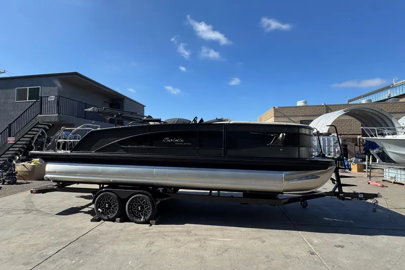 Slide: The Image of 2026 Barletta Lusso 23UC pontoon boat on trailer, parked outdoors under clear sky. - 124