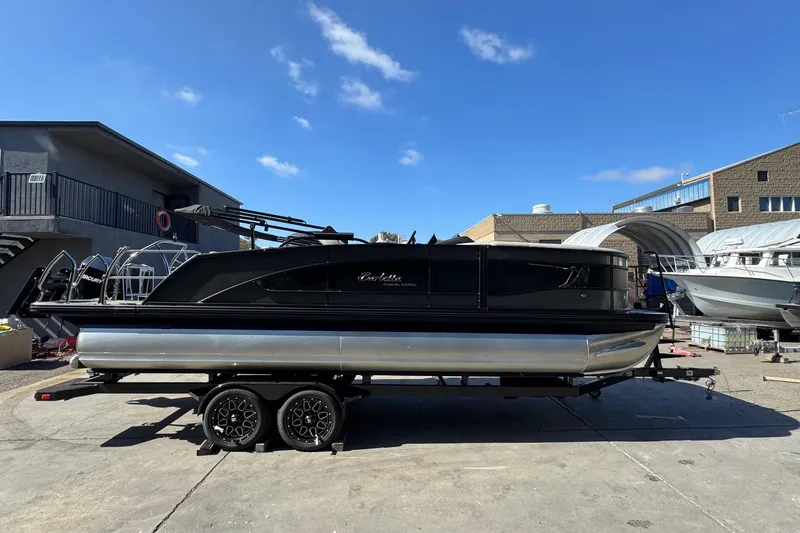 Slide: The Image of 2026 Barletta Lusso 23UC pontoon boat on trailer, parked outdoors under clear blue sky. - 126