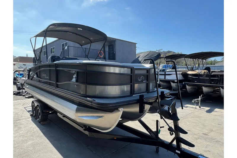 Slide: The Image of 2026 Barletta Lusso 23UC pontoon boat on trailer, parked outdoors under clear sky. - 183