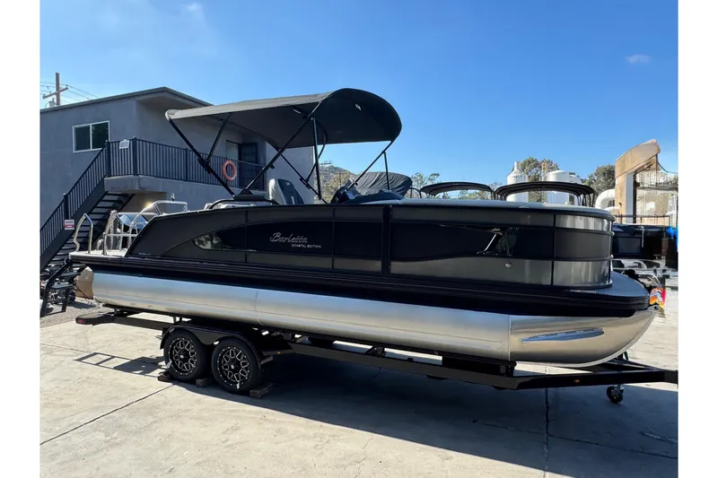 Slide: The Image of 2026 Barletta Lusso 23UC pontoon boat on trailer, parked outdoors under clear sky. - 184