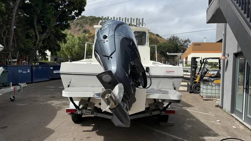 Slide: The Image of 2025 Defiance Admiral 220 EX boat with outboard motor, parked outdoors. - 13