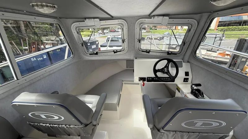 Slide: The Image of Interior of 2025 Defiance Admiral 220 EX boat, featuring helm and seating area. - 19