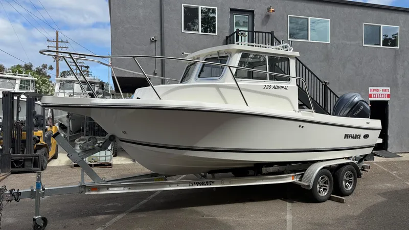 Slide: The Image of 2025 Defiance Admiral 220 EX boat on trailer, parked outside a building. - 2