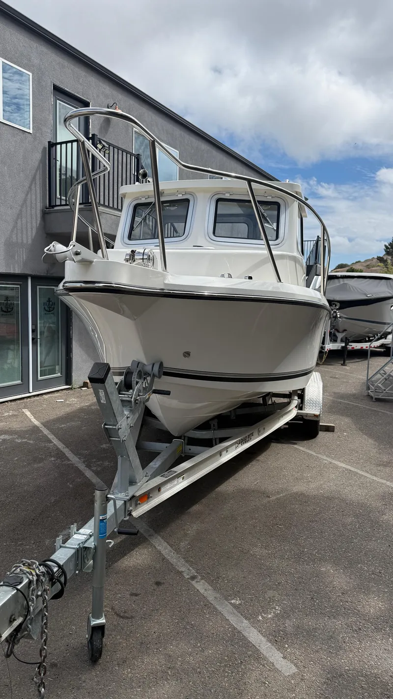 Slide: The Image of 2025 Defiance Admiral 220 EX boat on trailer, parked outdoors under cloudy sky. - 4