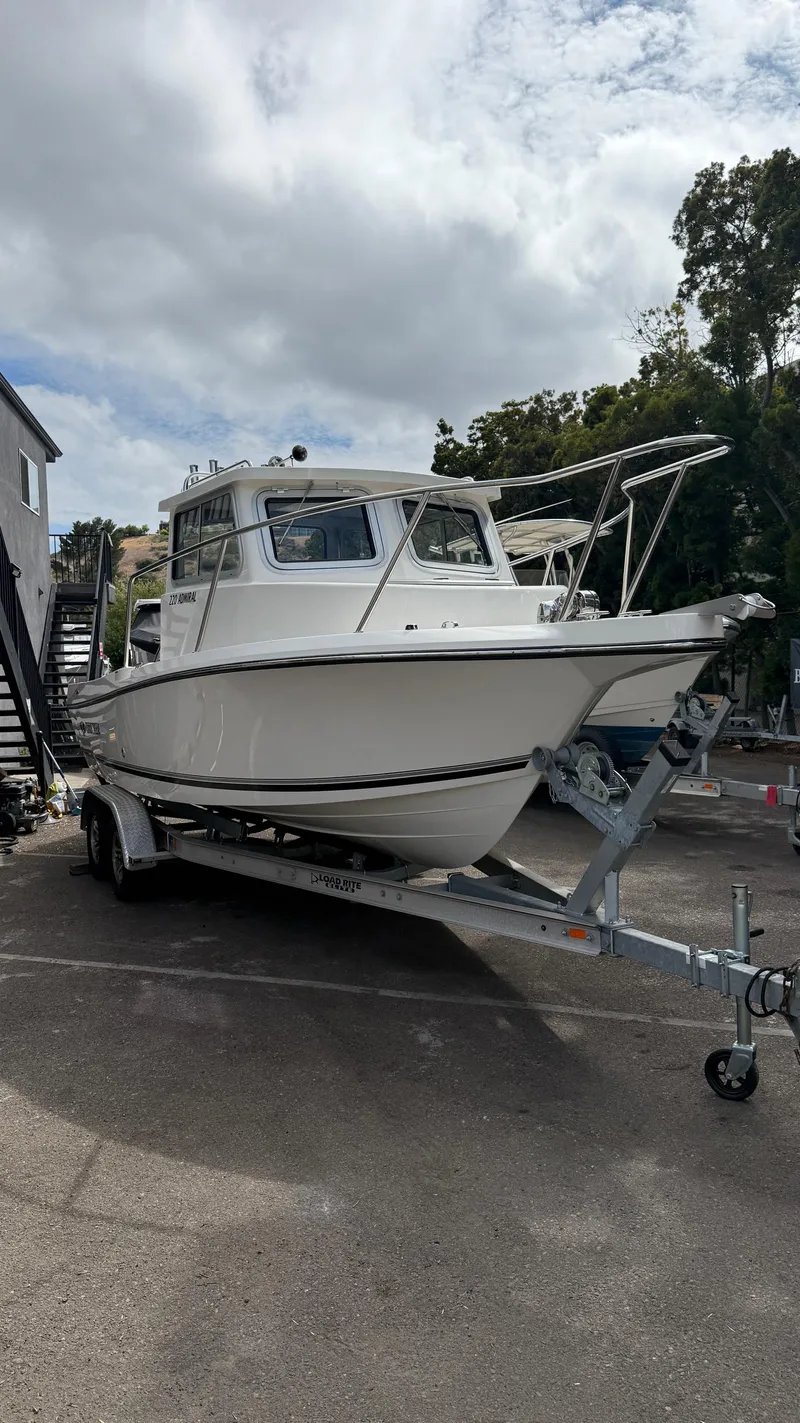 Slide: The Image of 2025 Defiance Admiral 220 EX boat on trailer, parked outdoors under cloudy sky. - 6