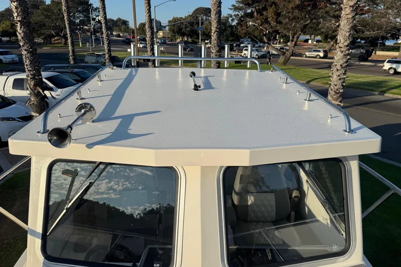 Slide: The Image of 2025 Defiance Admiral 250 EX boat roof with railings and horn, parked near palm trees. - 102