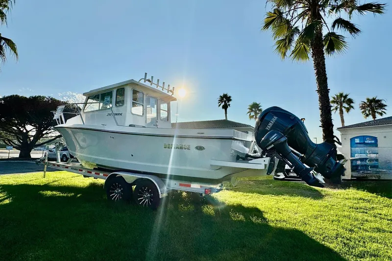 Slide: The Image of 2025 Defiance Admiral 250 EX boat on trailer, sunny day, palm trees in background. - 11