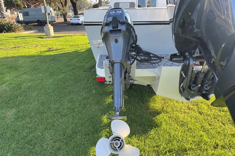 Slide: The Image of Outboard motor on 2025 Defiance Admiral 250 EX boat, parked on grass. - 13