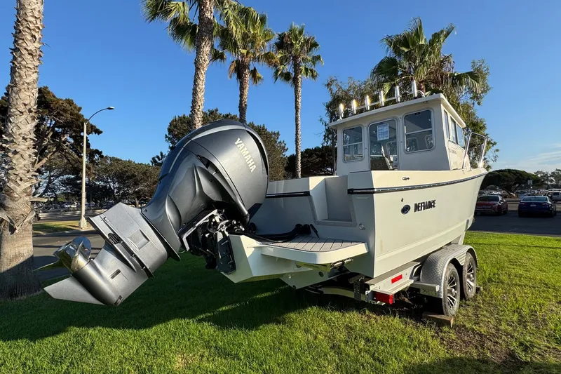 Slide: The Image of 2025 Defiance Admiral 250 EX boat on trailer, parked on grass with palm trees. - 16