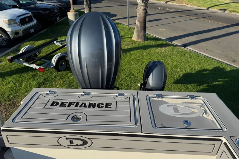 Slide: The Image of 2025 Defiance Admiral 250 EX boat with outboard motor, parked on grass near road. - 31