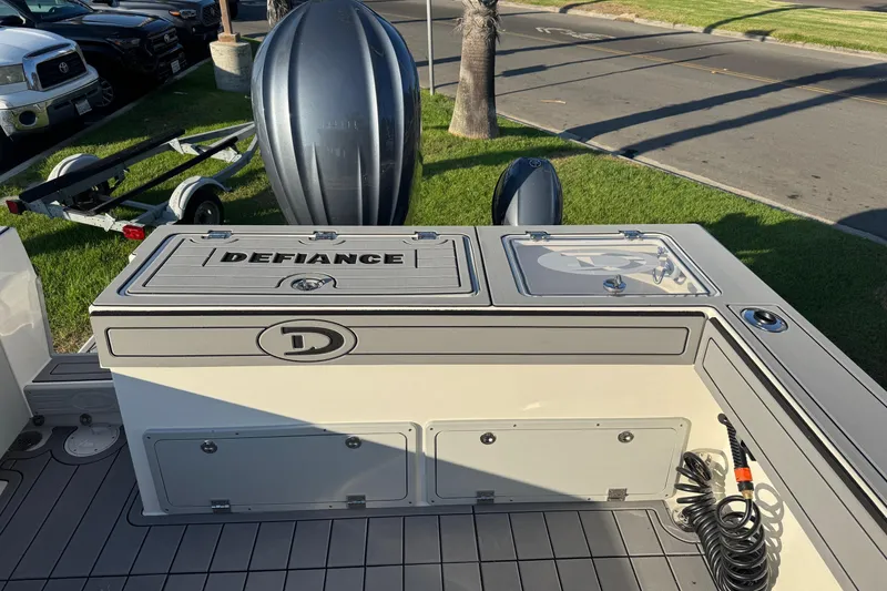Slide: The Image of 2025 Defiance Admiral 250 EX boat deck with storage compartments and motor, parked on grass. - 33