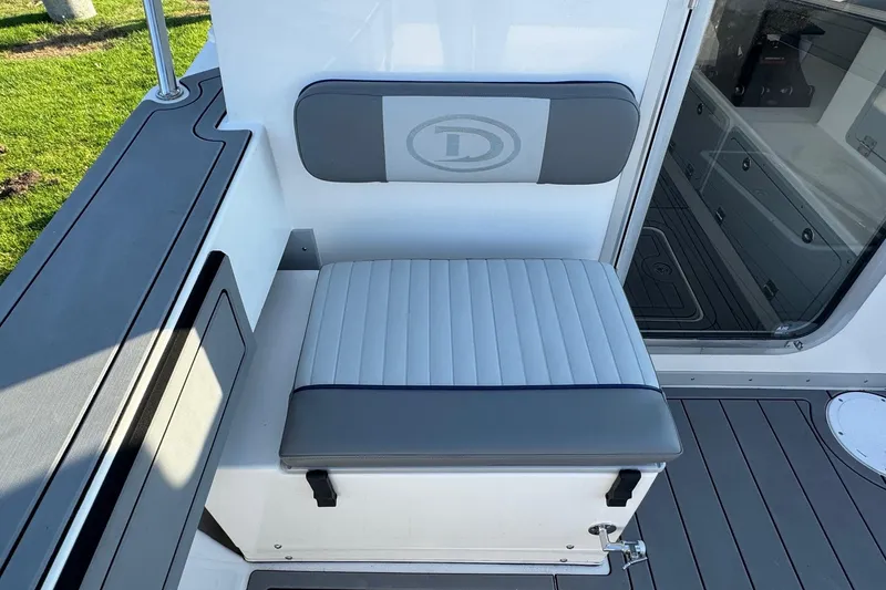 Slide: The Image of Defiance Admiral 250 EX 2025 boat seat with gray and white upholstery, docked on a sunny day. - 43